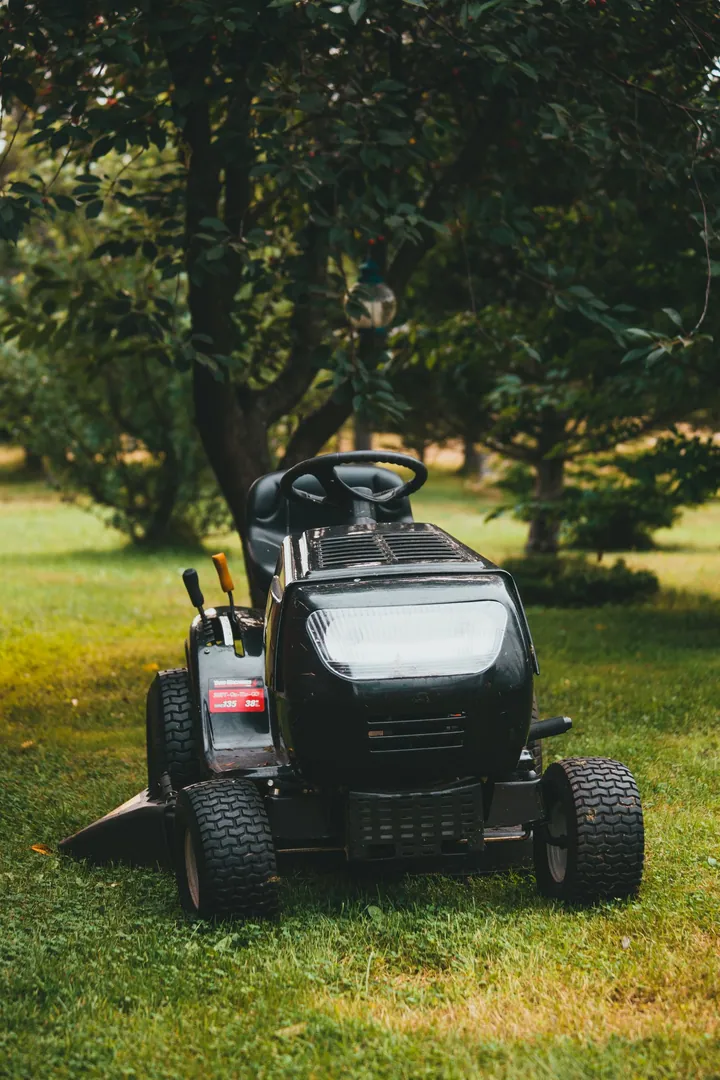 A riding mower on a tree-lined lawn